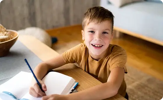 Student smiling while taking notes at home